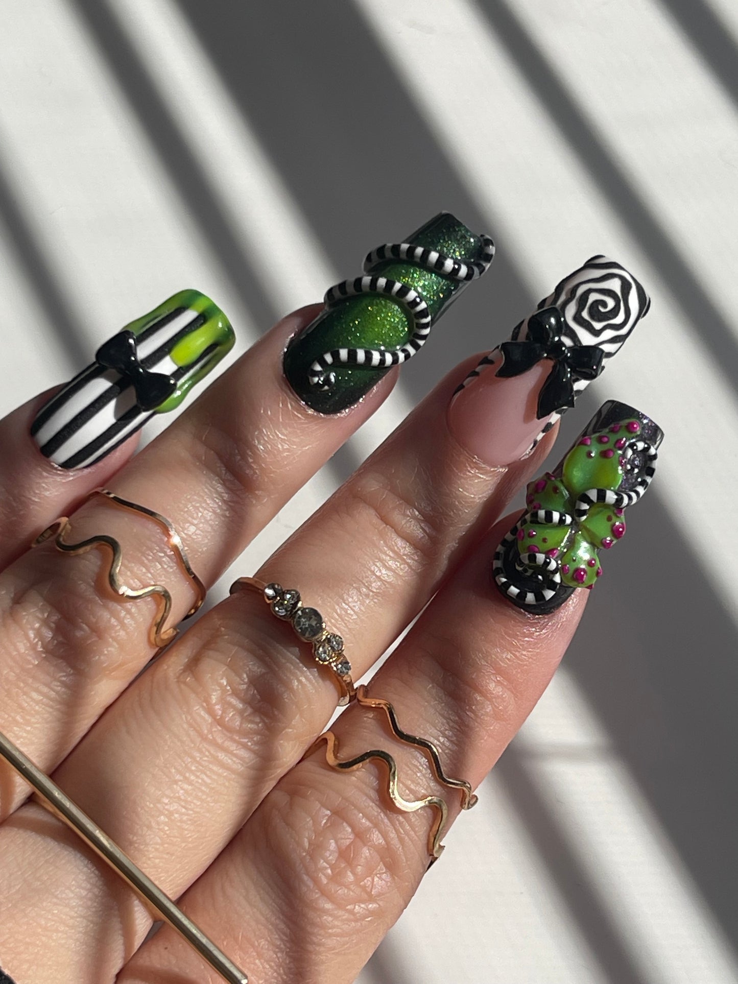 Hand with green and black nail art on a light background