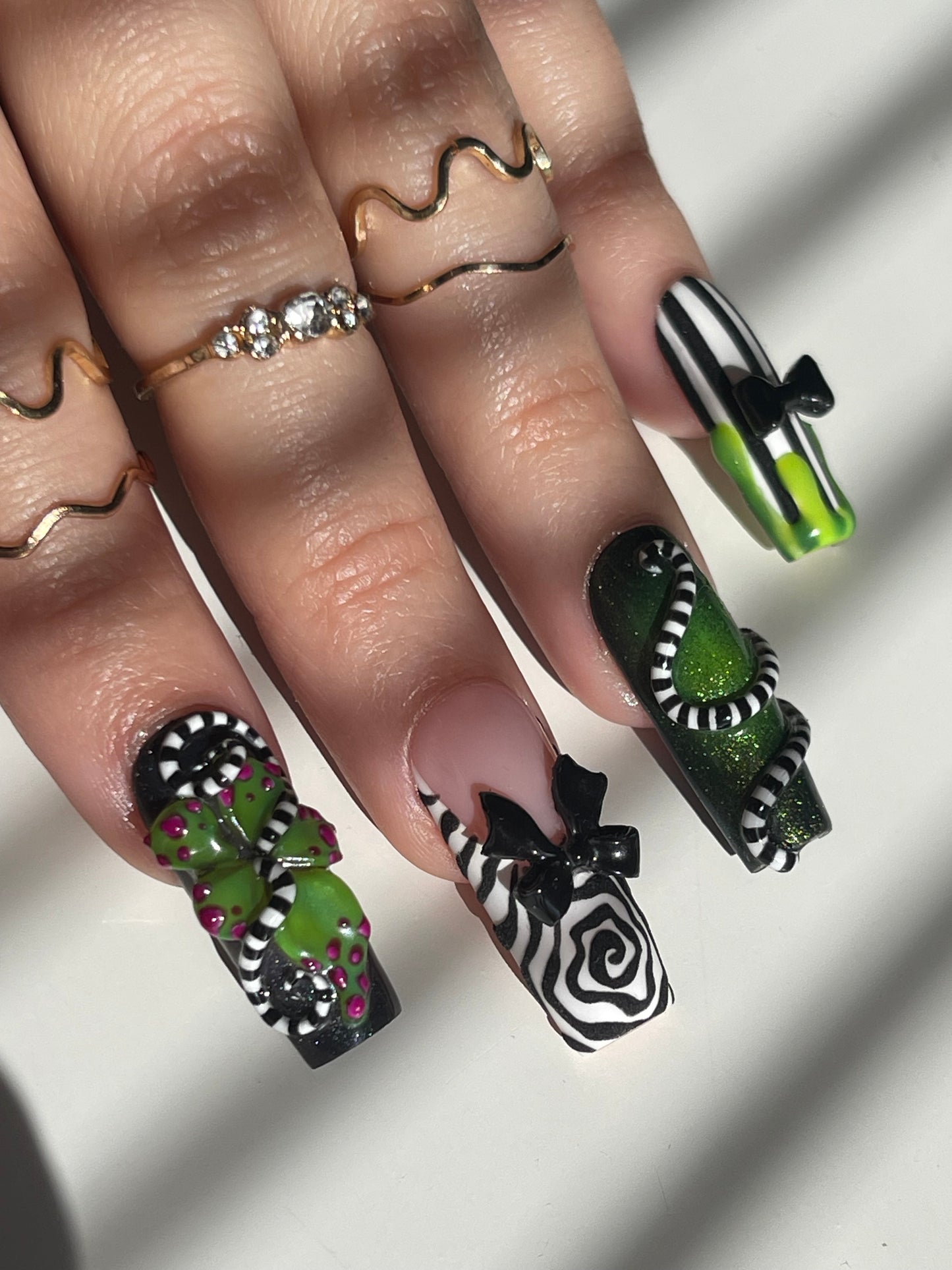 Close-up of a hand with intricately designed nails and multiple rings.