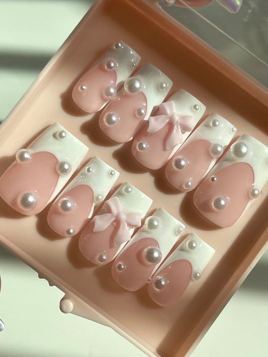 Set of pink and white nail designs with pearls in a pink case.