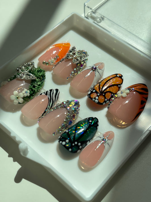 Decorative nail art with butterfly and flower designs on a white tray.