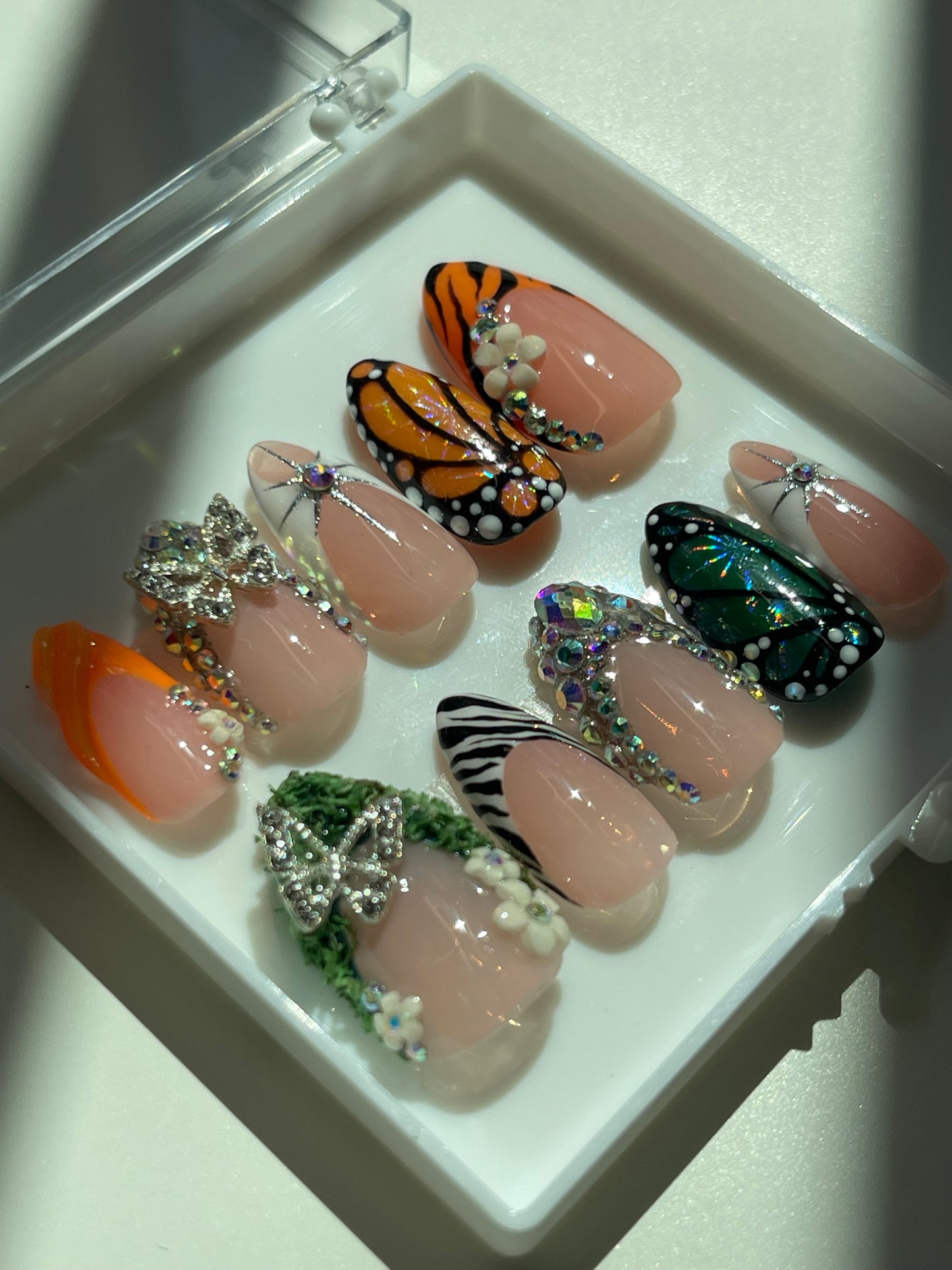 Decorative nail art with butterfly and zebra designs on a white tray.