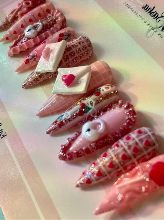Decorative false nails with heart designs and a pink base on a colorful background.