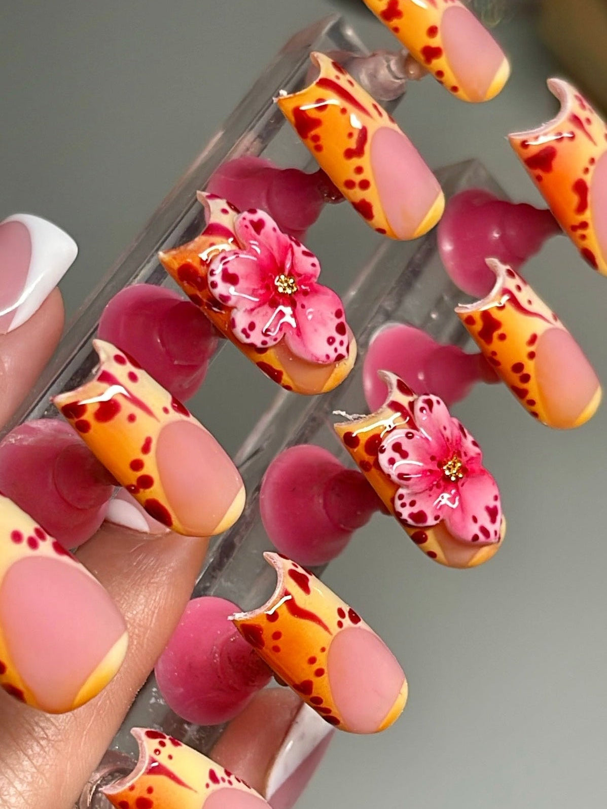 Close-up of a hand with colorful floral nail art on a neutral background