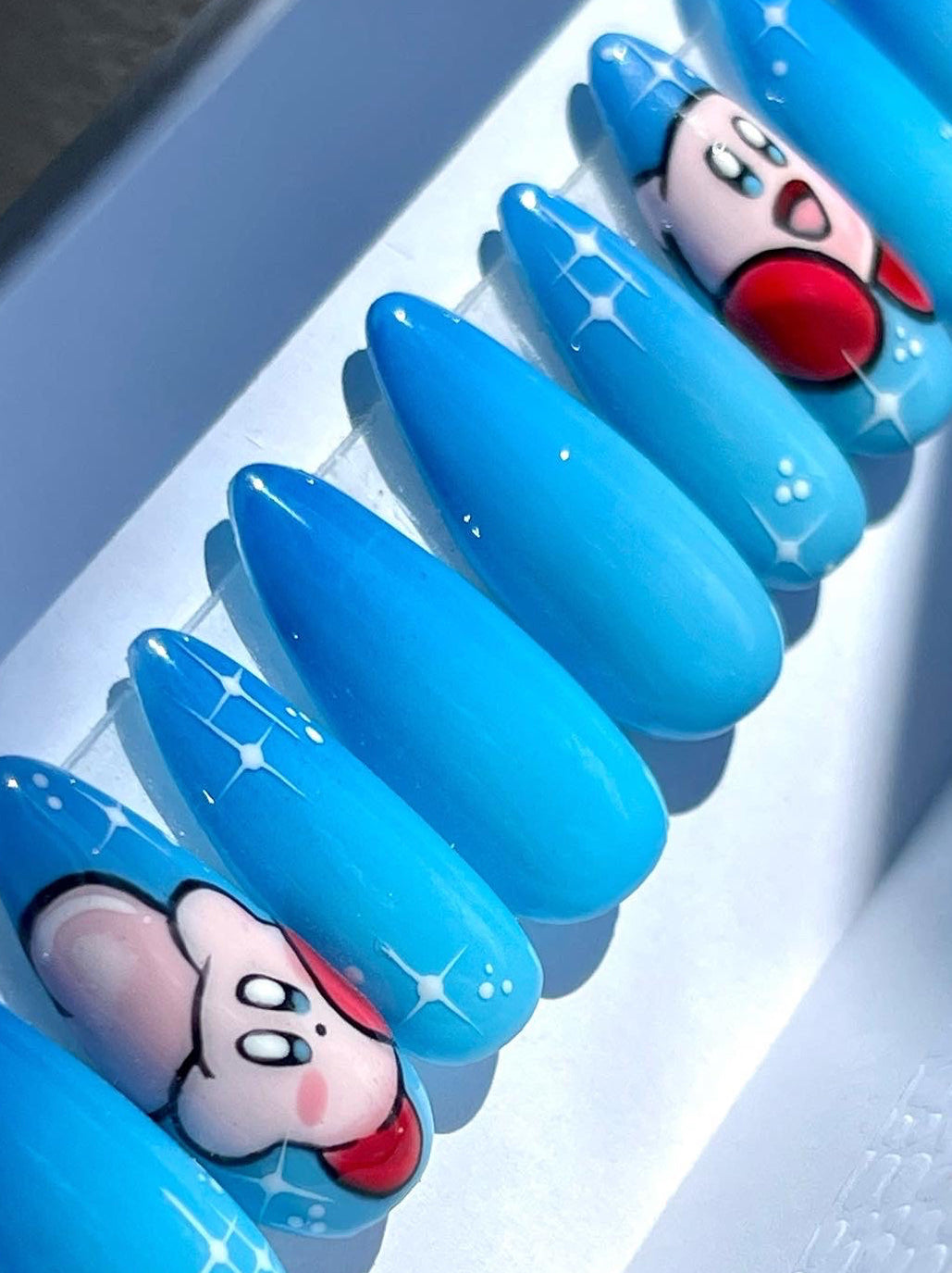 Blue nail art with cartoon character design on a white tray
