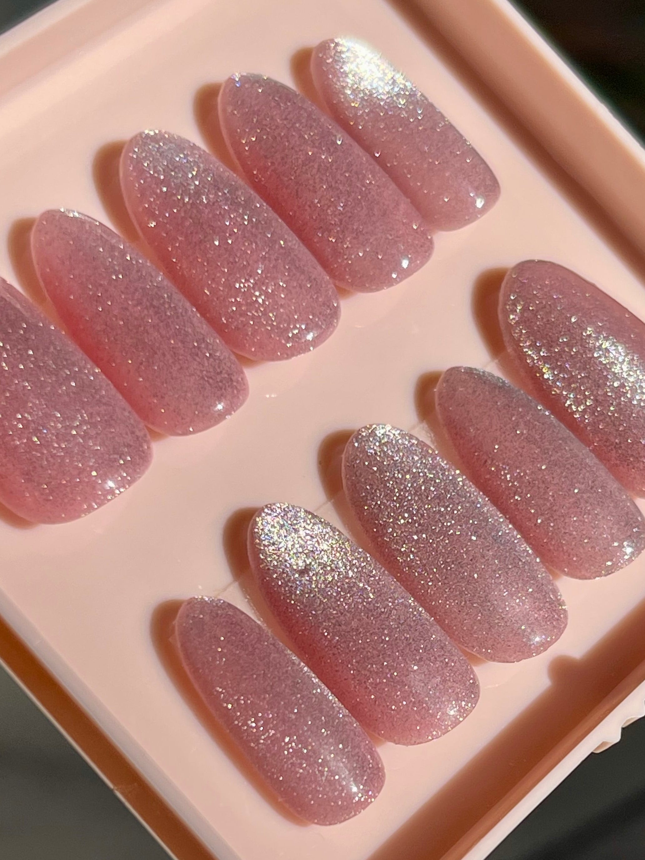 Set of pink glittery false nails in a clear case