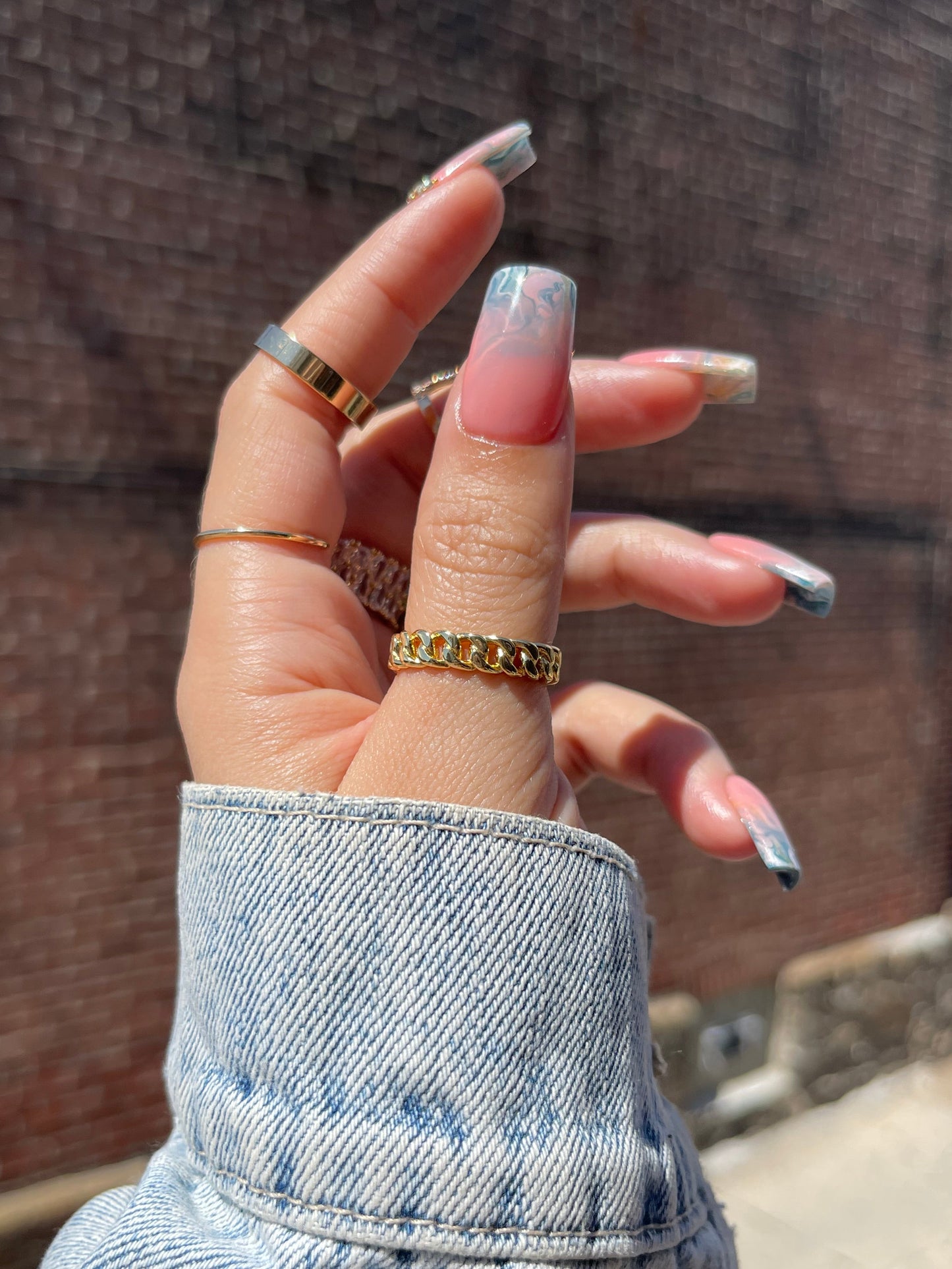 Hand with multiple gold rings on a wooden surface