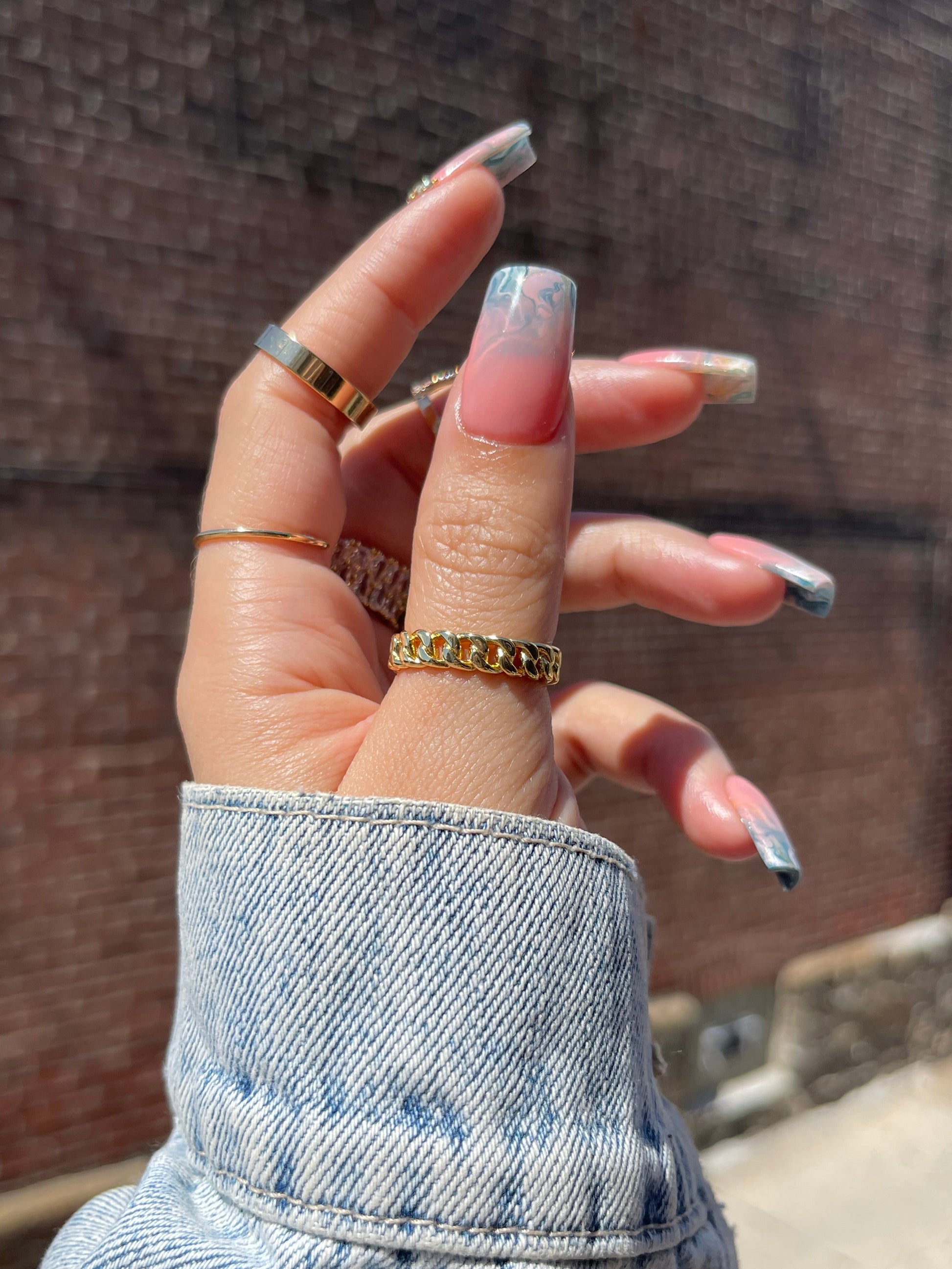 Hand with multiple gold rings on a wooden surface