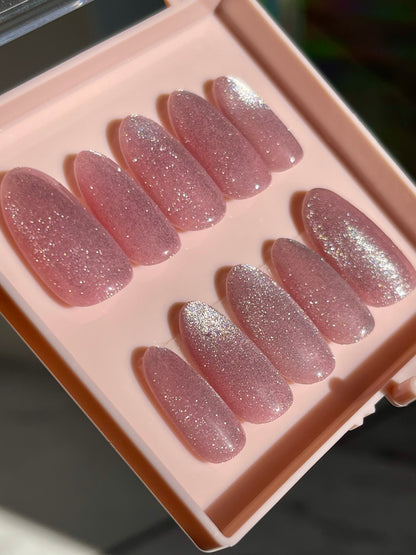 Set of pink glittery false nails in a display case.