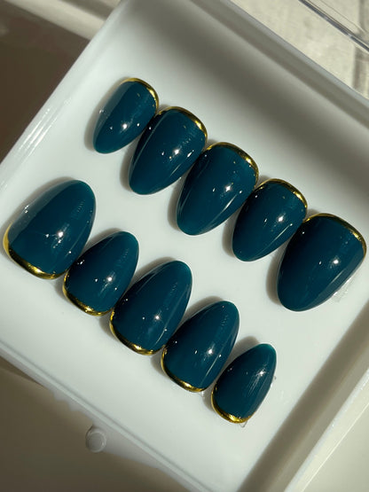 Set of blue nail extensions with gold tips on a white tray