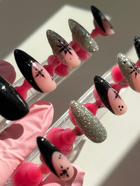 Nail art display with black, gold, and pink designs on a white background