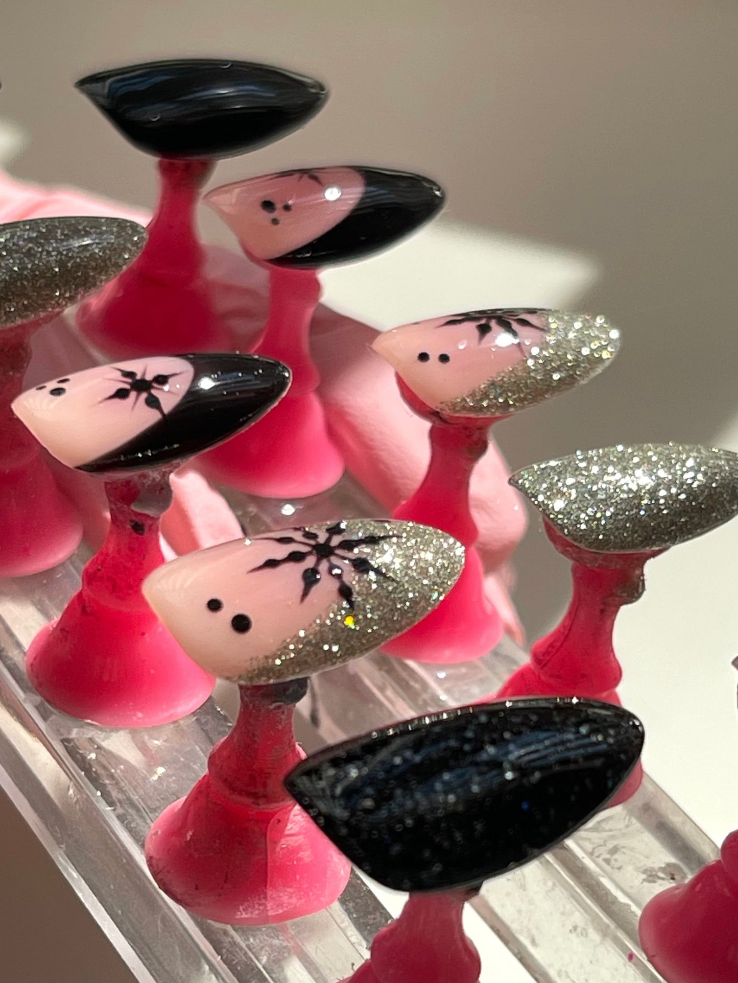 Set of pink and black decorative nails on a clear stand