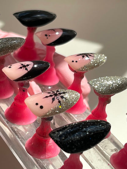 Set of pink and black decorative nails on a clear stand