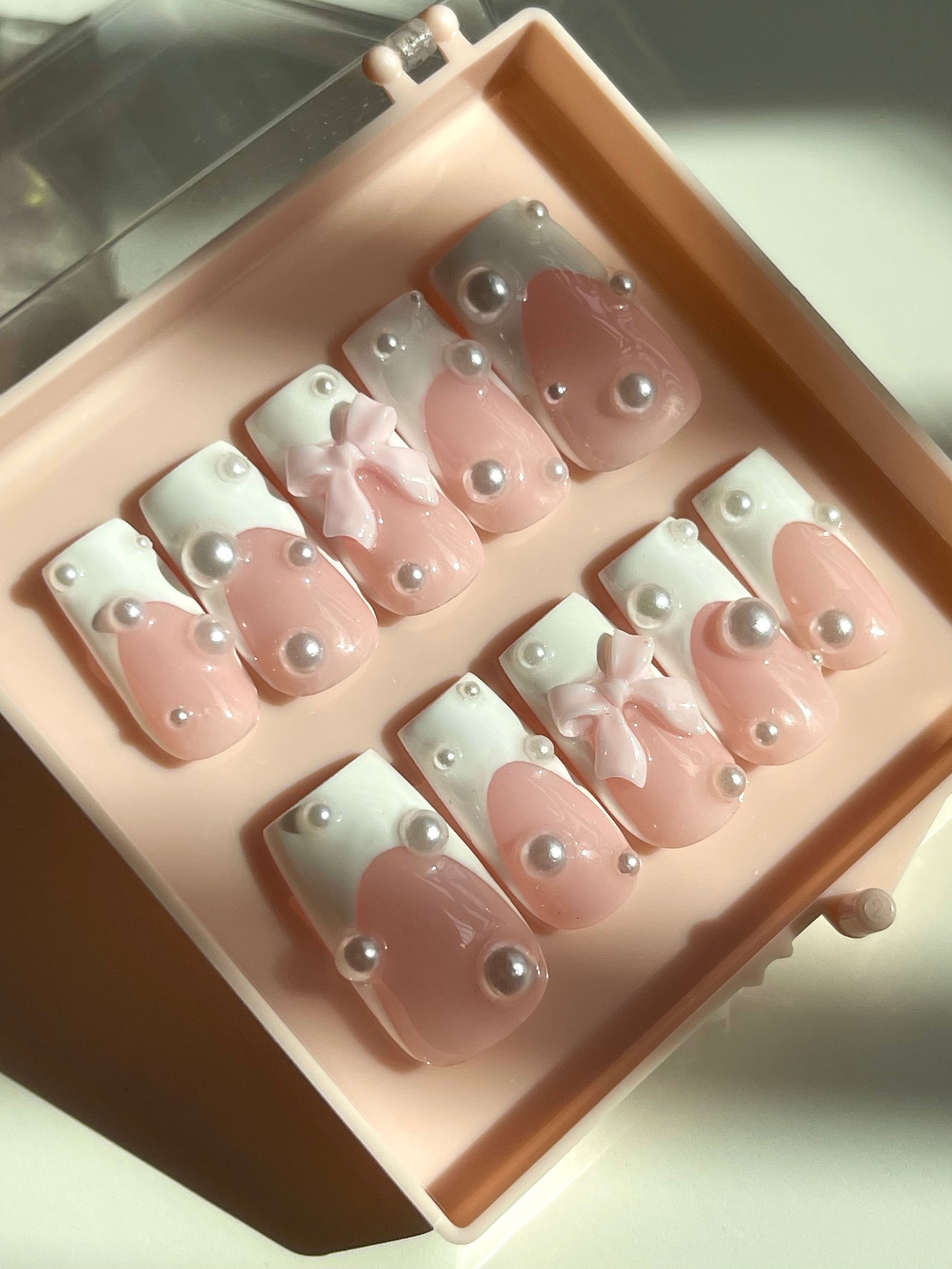 Set of pink nail art designs with bows and pearls in a box