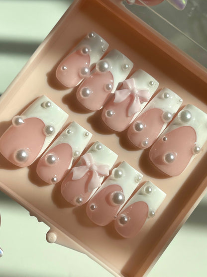 Set of pink and white nail designs with pearls in a pink case.