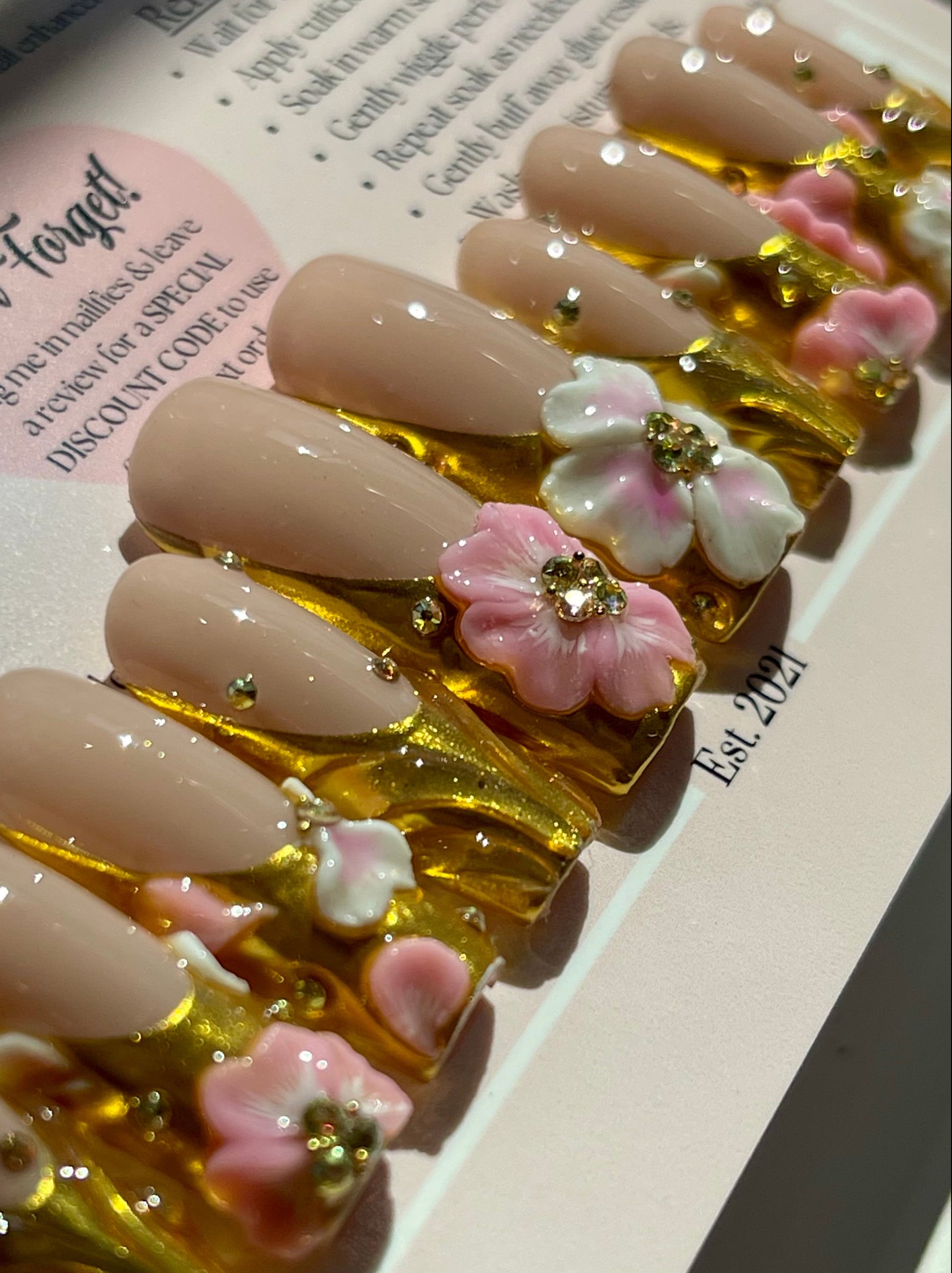 Nails with gold and floral decorations on a instructions card