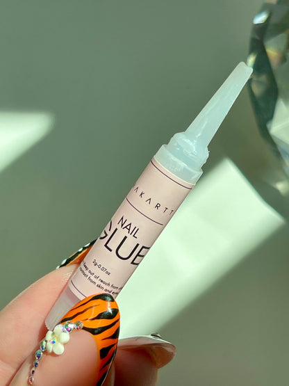 Hand holding a bottle of Makartt nail glue with a white background