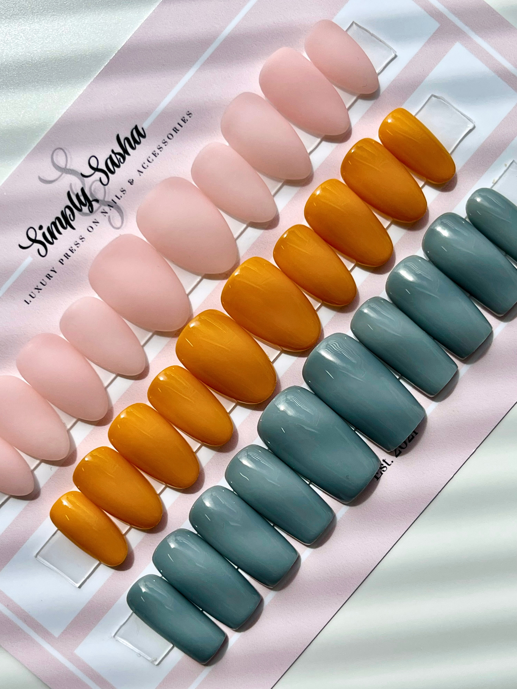 Set of press-on nails in pink, orange, and blue gradient on a Simply Sasha card.