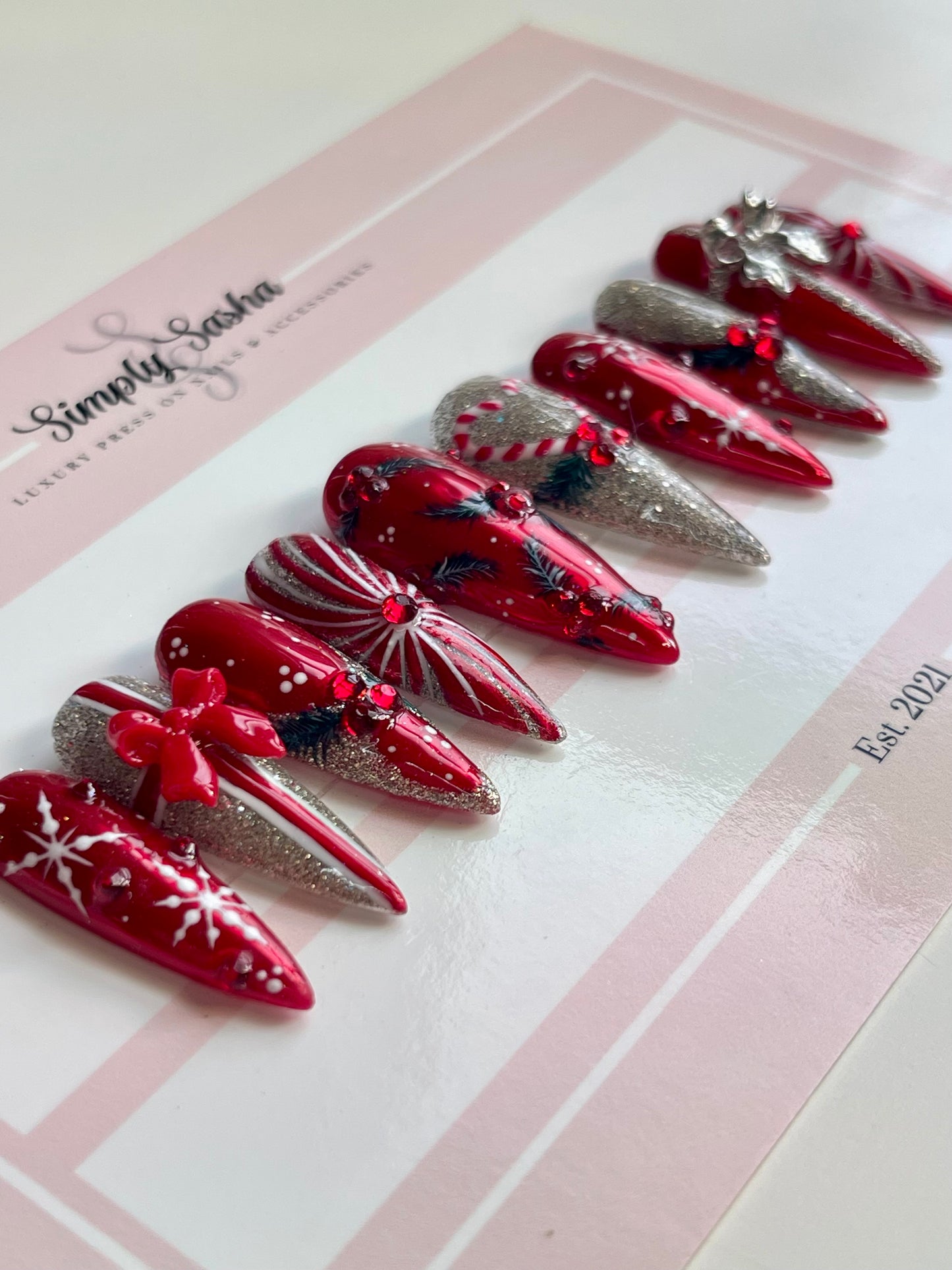 Red and silver decorative nails on a Simply Sasha branded card.
