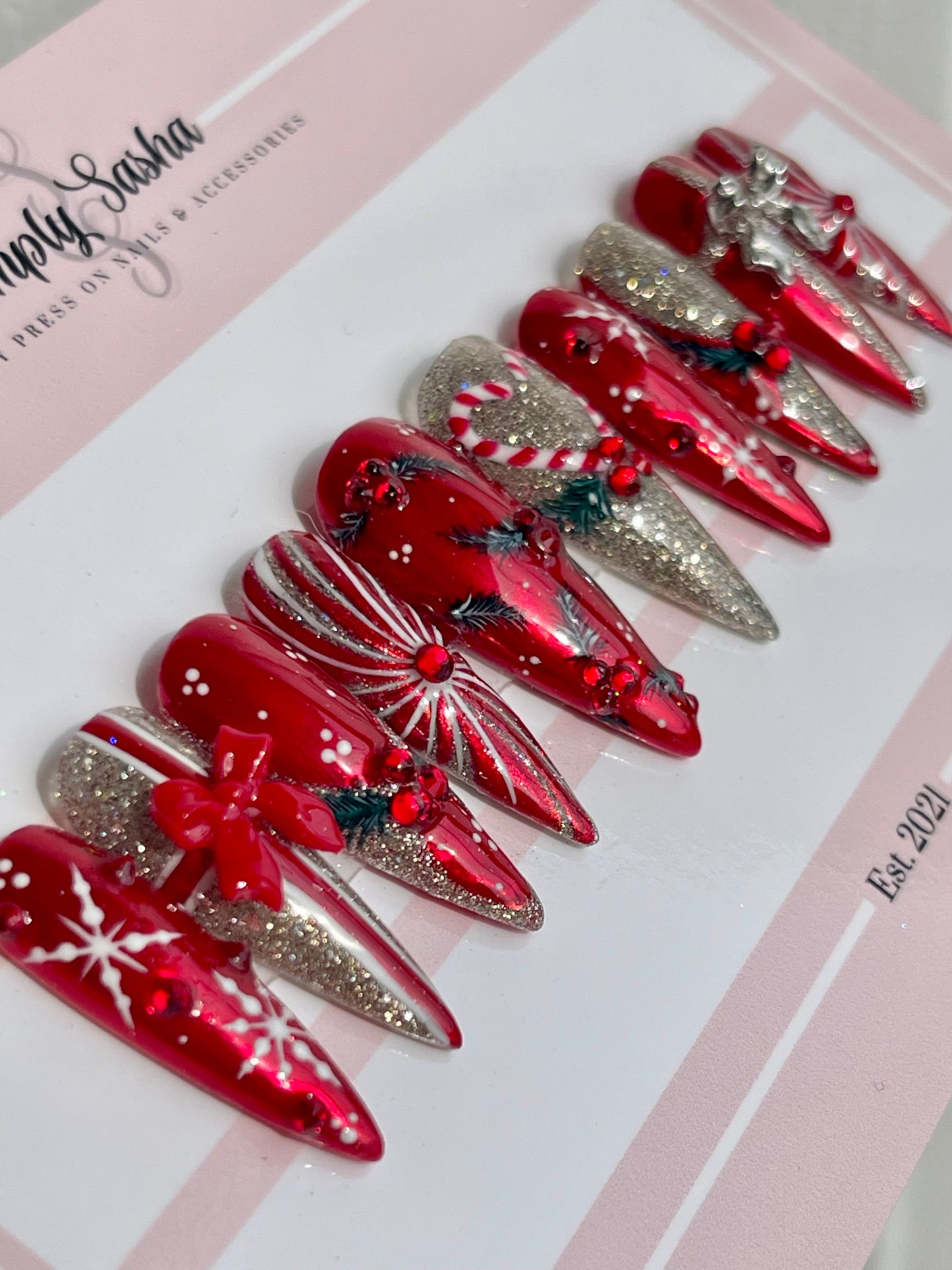 Set of red and silver Christmas-themed nail art designs on a white background with 'Simply Sasha' branding.