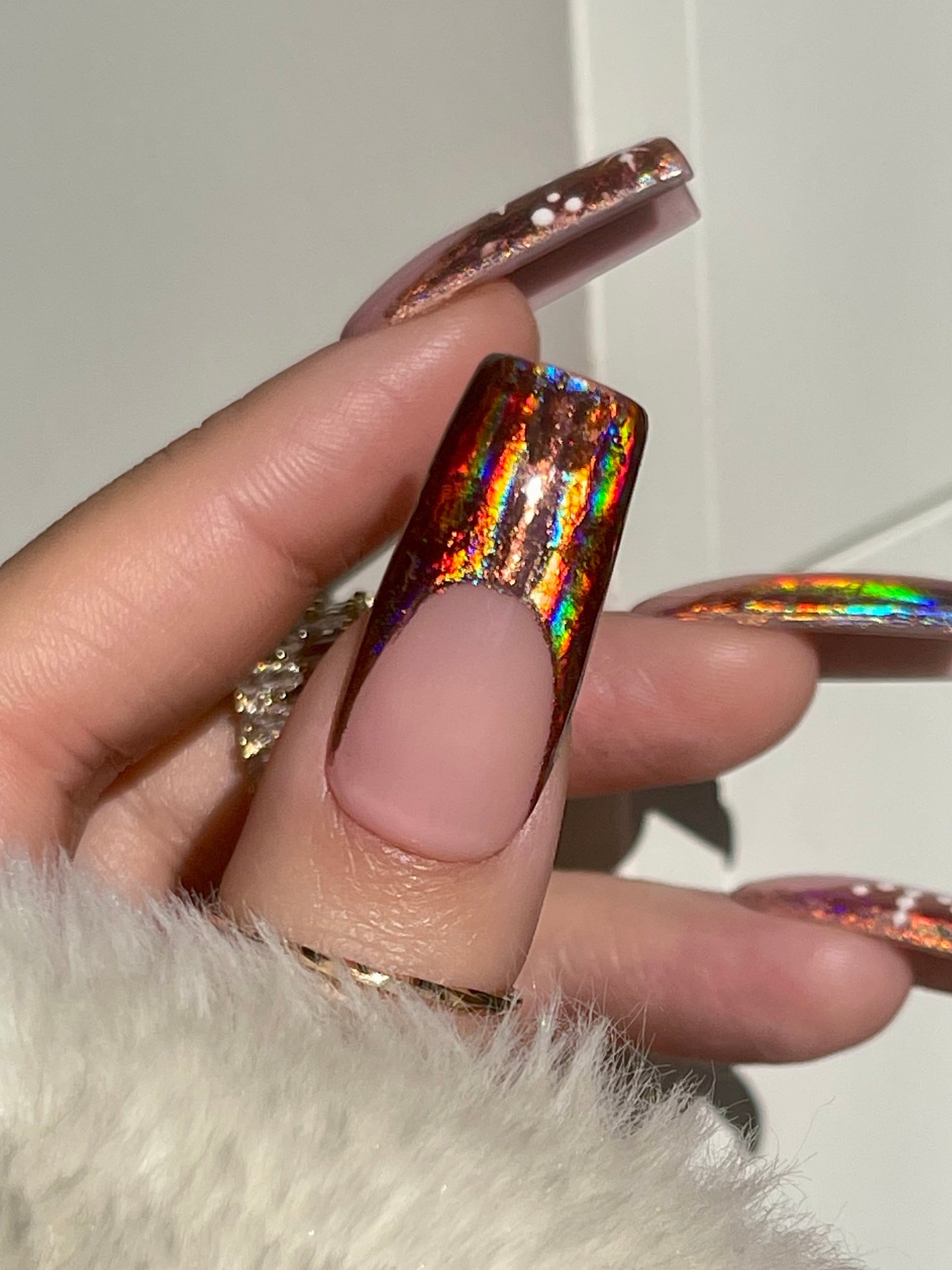 Hand with iridescent nail polish on a white background
