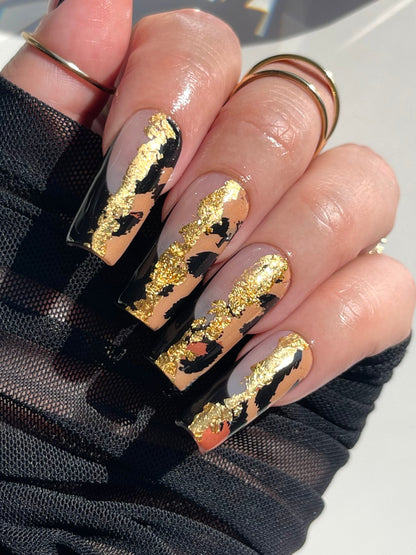 Nails with black and gold design on a white background