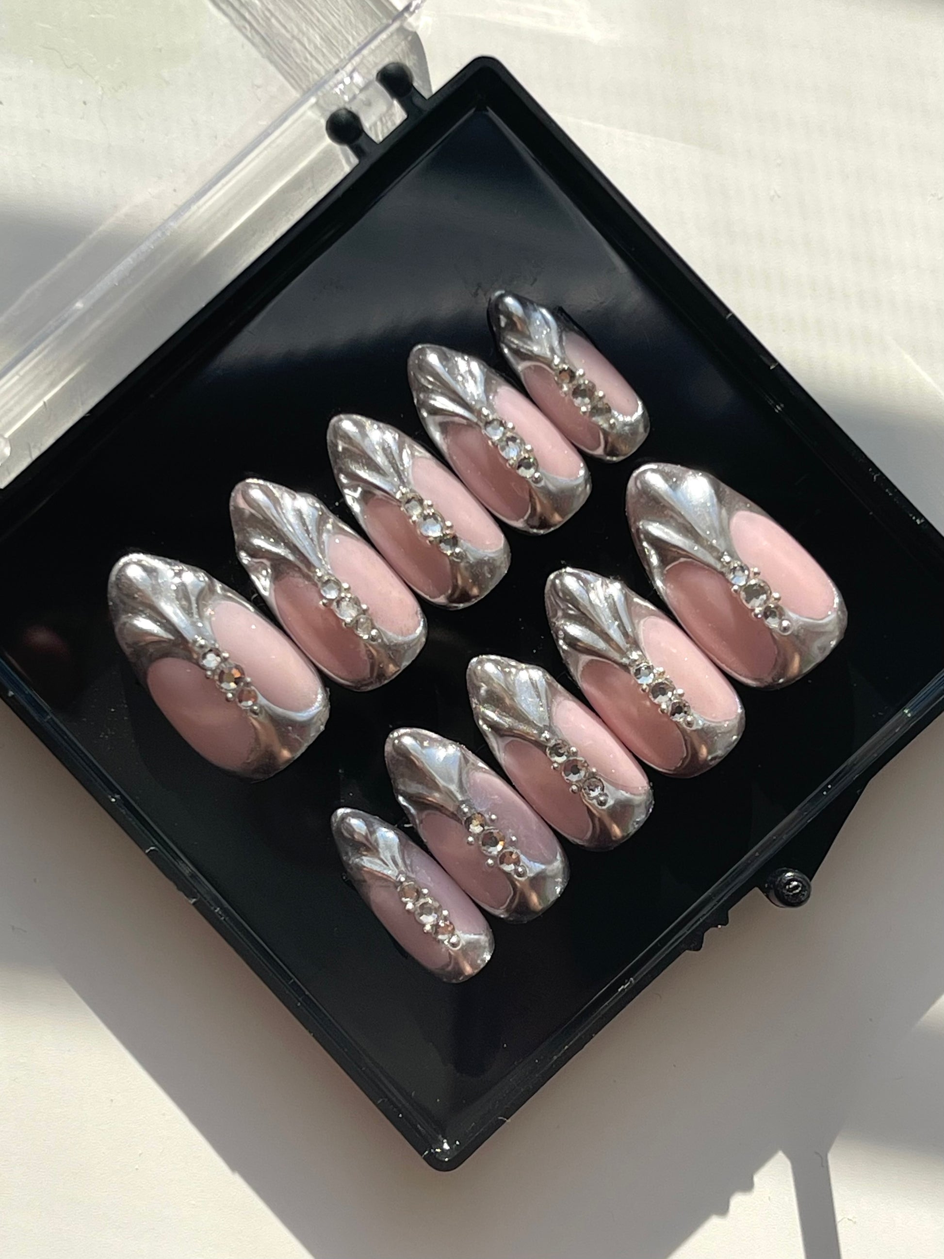 Set of decorative false nails with a metallic finish in a black case.