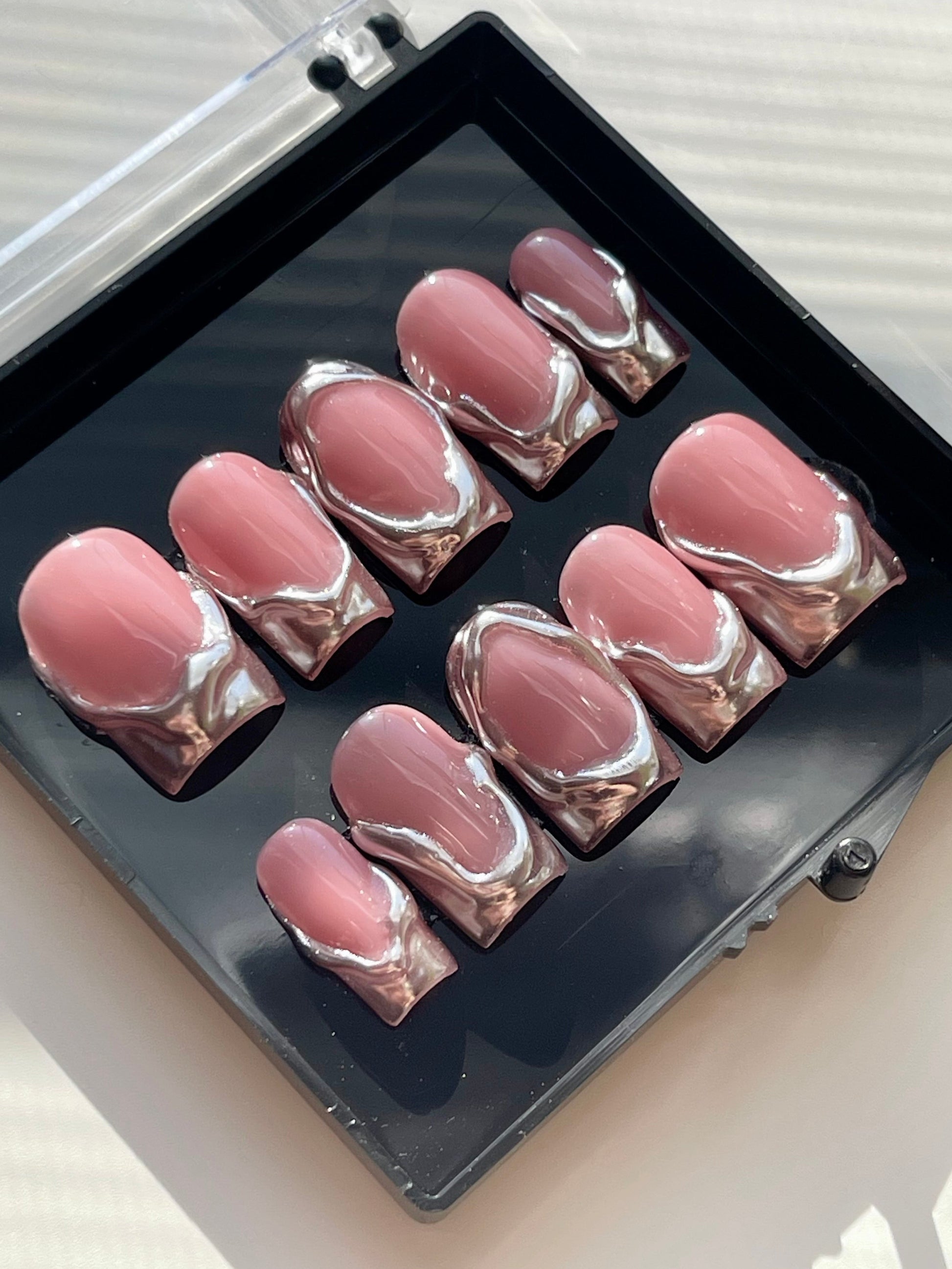 Set of pink and silver nail art designs in a case on a light background