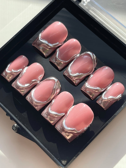 Set of pink nail pads with silver swirl design in a black case.