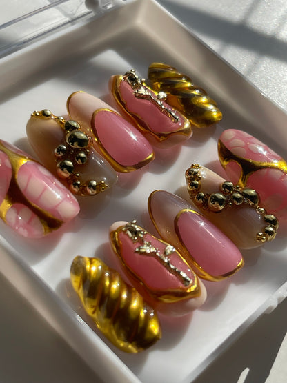 Nail art display with pink and gold designs on a white tray.